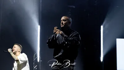 Dos integrantes de Hijos de la Ruina cantan con micrófono bajo focos blancos en el Multiusos Sánchez Paraíso de Salamanca