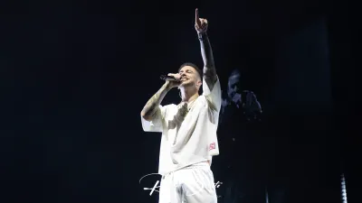 Integrante de Hijos de la Ruina, vestido de blanco, canta y señala al cielo en el Multiusos Sánchez Paraíso de Salamanca