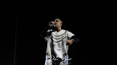 Un miembro de Hijos de la Ruina canta al micrófono, con camiseta blanca de cadenas, en el Multiusos Sánchez Paraíso