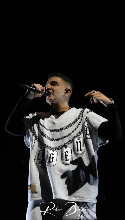 Un cantante de Hijos de la Ruina canta con micrófono en el Multiusos Sánchez Paraíso de Salamanca, con camiseta blanca de cadenas