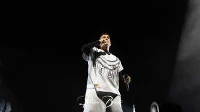 Cantante de Hijos de la Ruina con camiseta blanca de cadenas y micrófonos en ambas manos, sobre un escenario oscuro en Salamanca