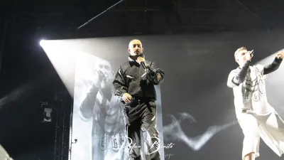 Dos raperos de Hijos de la Ruina cantan con micrófono en el escenario del Multiusos Sánchez Paraíso, uno de negro y otro de blanco