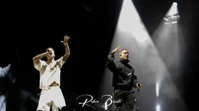 Dos integrantes de Hijos de la Ruina cantan con el brazo en alto bajo focos blancos en el Multiusos de Salamanca