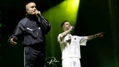 Dos miembros de Hijos de la Ruina, uno de negro y otro de blanco señalando al público, cantan en el Multiusos de Salamanca